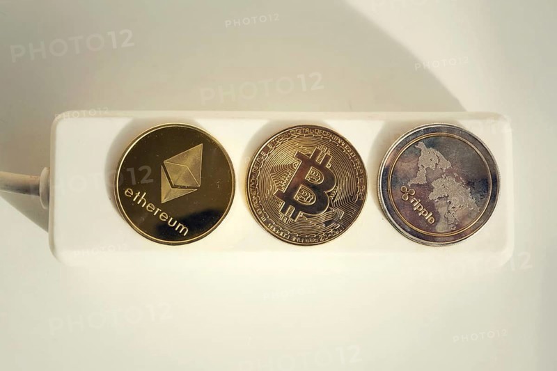 Bitcoin, Ethereum and Ripple coins lying on power strip extension cord with 3 sockets, largest cryptocurrencies by market capitalization, cryptocurrency investing, energy consumption and footprint concept Prague Czech republic