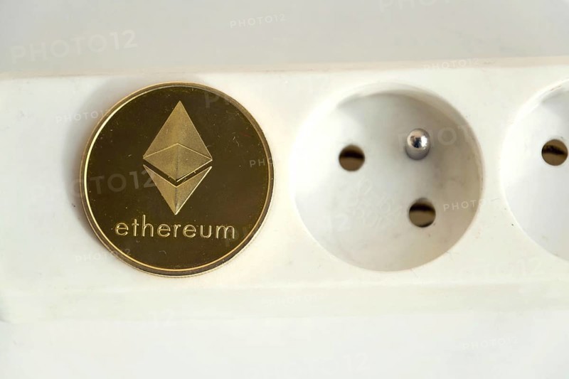 Ethereum coin lying on power strip extension cord with empty socket, cryptocurrency energy consumption and footprint concept, isolated on white background Prague Czech republic