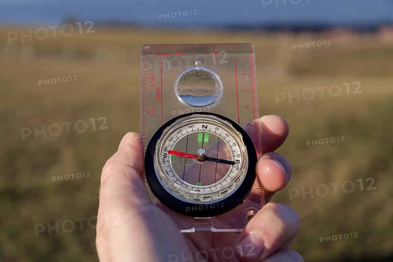 Male hand holding glass compass, nature in background, sunny autumn day, life change and new years resolutions conceptMale hand holding glass compass, nature in background, sunny autumn day, life change and new years resolutions concept Prague Czech republic
