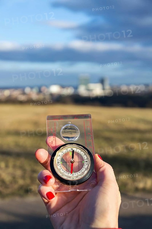 Female hand holding glass compass, nature in background, sunny autumn day, life change and new years resolutions concept Prague Czech republic