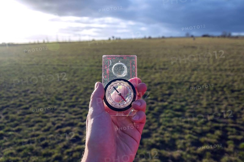 Male hand holding glass compass, nature in background, sunny autumn day, life change and new years resolutions concept Prague Czech republic