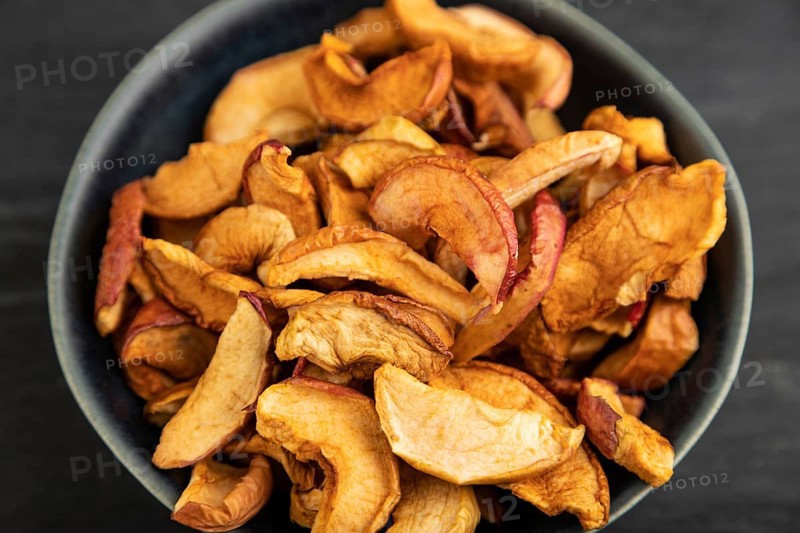 Dried Apples in ceramic bowl on black wooden background. Side view, close up. healthy food, minimalism. sweet, selective focus
