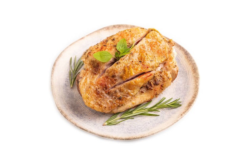 Fried Turkey Thigh with spices and rosemary on plate isolated on white background. side view, close up
