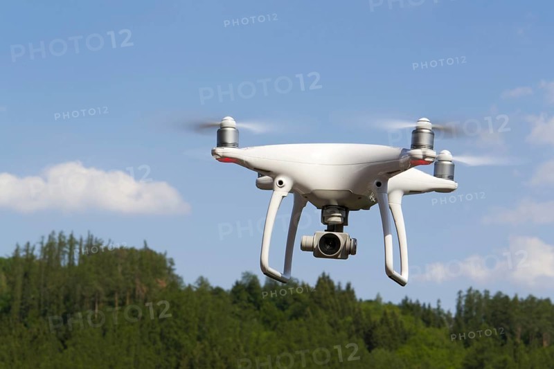 White drone quadrocopter with camera flying over forest Pisek Czech republic