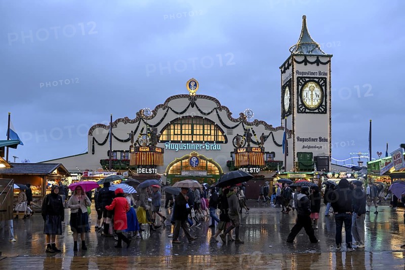 Oktoberfest visitors with umbrellas, rainy meadows, Augustiner festival tent, Munich, Bavaria, Germany