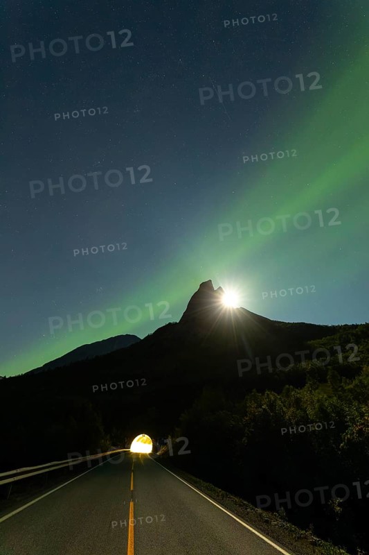 National mountain of Norway, Stetind in the Nordland under auroras and a full moon behind the summit. Entrance to the tunnel below the mountain