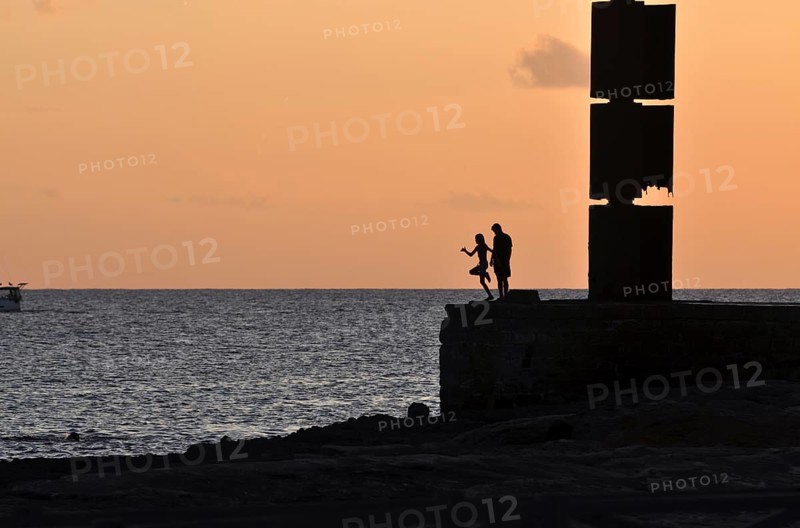 Silhouette of a girl jumping into the sea while a boy is watching, Majorca, balearics, spain