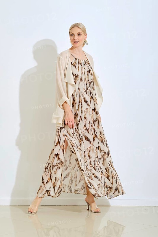 A stylish woman walks confidently in a beautiful, flowing dress with a unique pattern. The bright studio enhances her elegant look and the overall atmosphere is fresh and modern