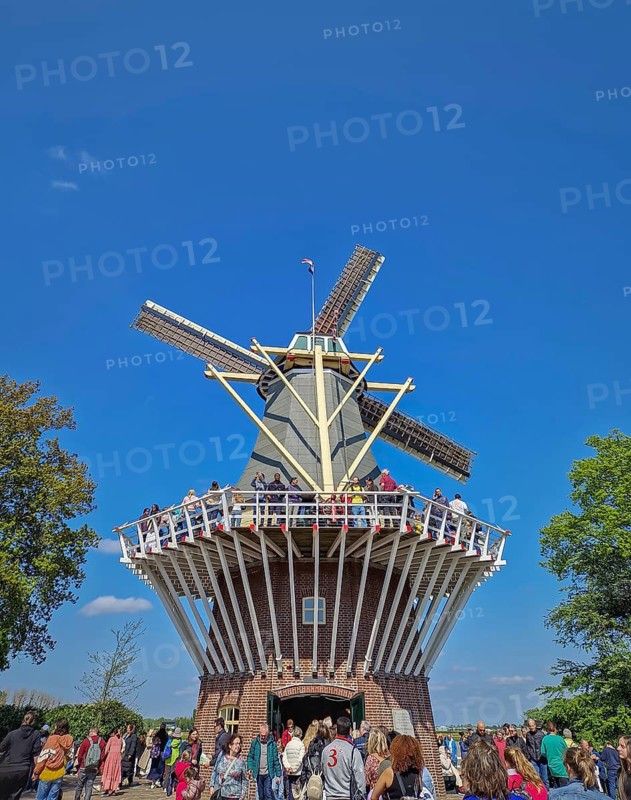 Lisse, Holland, Netherlands, April 25, 2025: the iconic brick windmill at Keukenhof, set against a clear blue sky and a large crowd of tourists gathering. Popular Dutch tourism landmark, Lisse, Holland, Netherlands