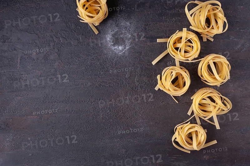 Tagliatelle on a dark textured background, top view, space for text