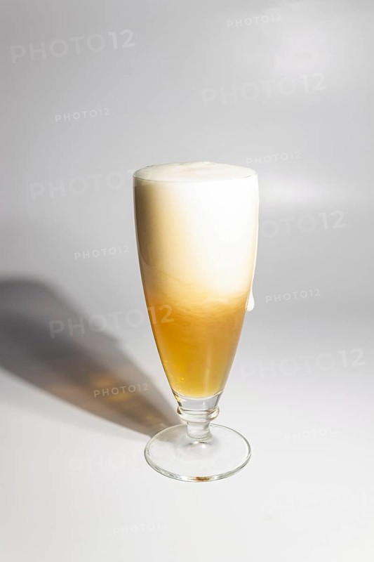 A drop of beer flows down a glass on a white background, copy space