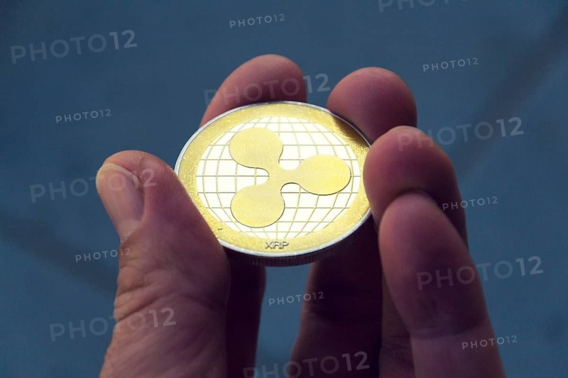 Silver gold ripple coin in hand, cryptocurrency investing concept