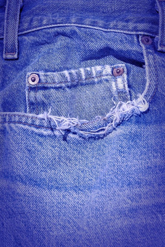 A Worn and tattered blue Jeans pocket
