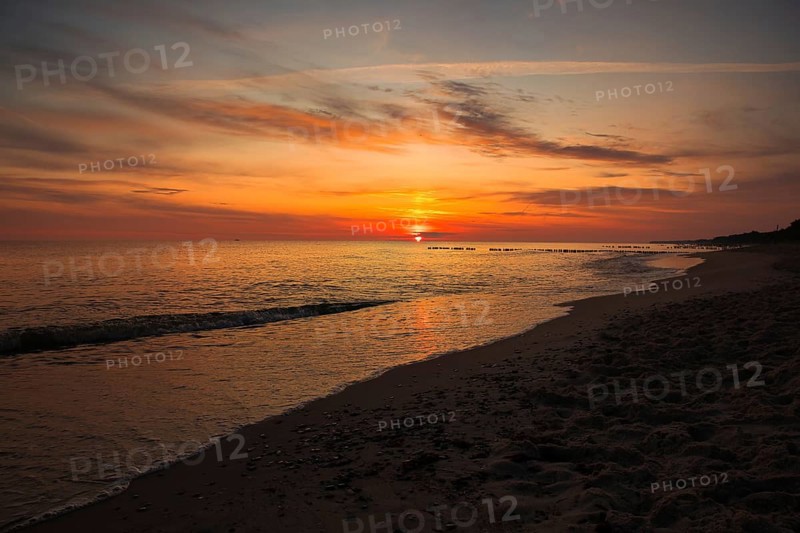 A serene sunset over the sea with golden skies and gentle waves lapping at the sandy beach. Sea Baltic, Poland, Kolobrzeg