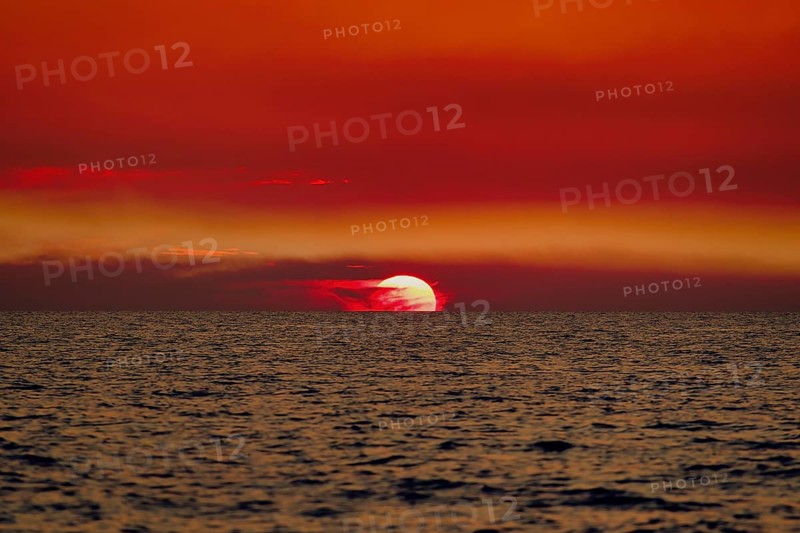 Sunset over the sea with a vivid red sky and gentle waves. Baltic, sea, Poland, Kolobrzeg