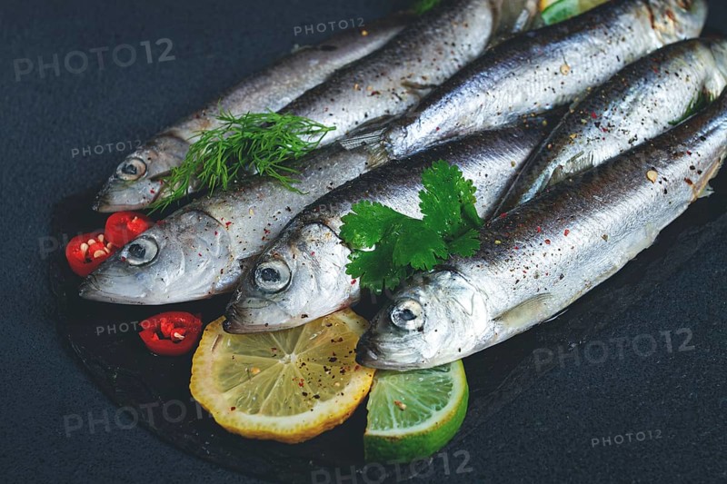 Fresh Herring fish, ready to cook, with herbs and spices, on black slate, in the kitchen