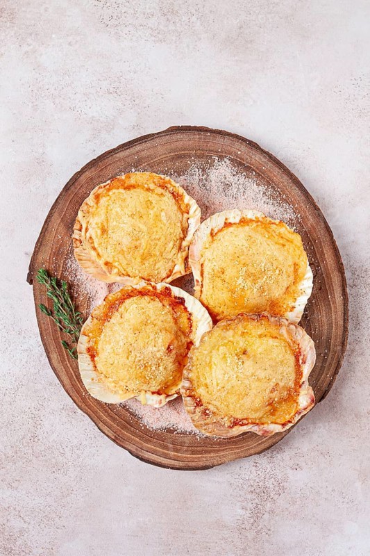 Scallop, baked in shells, with cheese and spices, on a cutting board, homemade