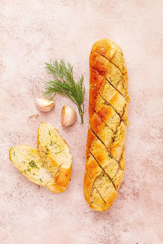 Freshly baked garlic bread with herbs and garlic on a light countertop