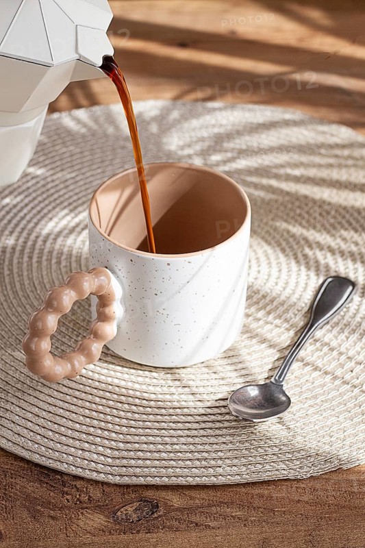Pouring fresh coffee into a ceramic cup, geyser coffee maker, natural light, breakfast