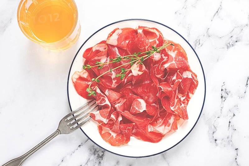 Plate with sliced cured meat, pork neck, prosciutto coppa, Italian delicacy
