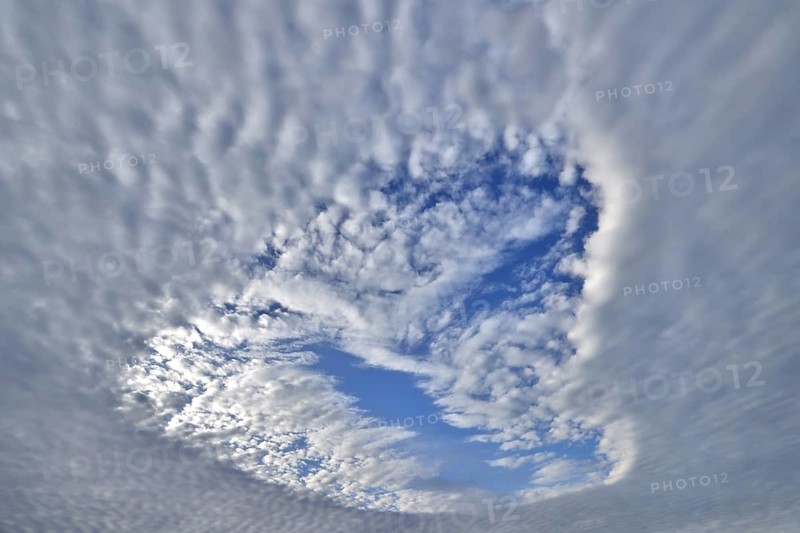 Heart-shaped hole in low-lying closed cloud cover provides a view of the blue sky with sheep clouds, Upper Bavaria, Bavaria, Germany