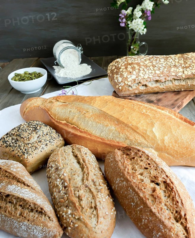 Various freshly baked artisanal breads and rolls presented on a white cloth on a rustic wooden table