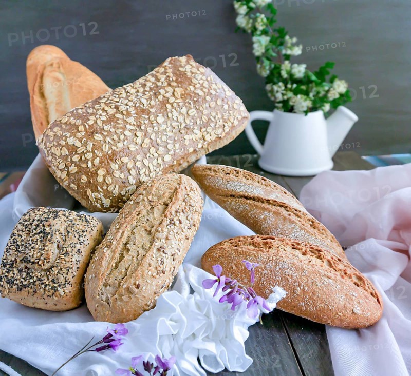 Various freshly baked artisanal bread loaves, including whole grain and sourdough, beautifully arranged on a rustic wooden table