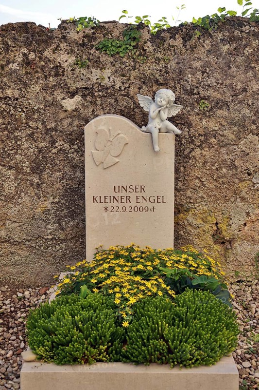 Children's grave with angel figure and beautiful floral decoration on a cemetery wall, Upper Bavaria, Bavaria, Germany