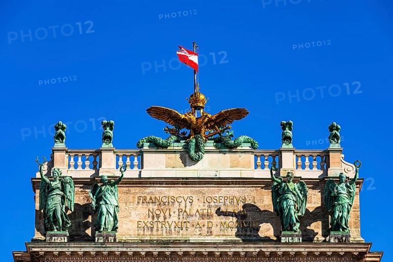 The roof with bronze statues, golden eagle and the Austrian national flag, above the main entrance to the new Hofburg Imperial Palace, Heldenplatz, Vienna, Austria