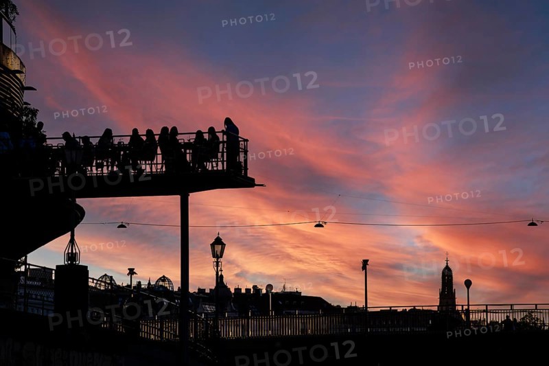 Visitors sit at sunset on the terrace of a cafe in the Urania am Danube Canal, Urania Observatory, Vienna, Austria