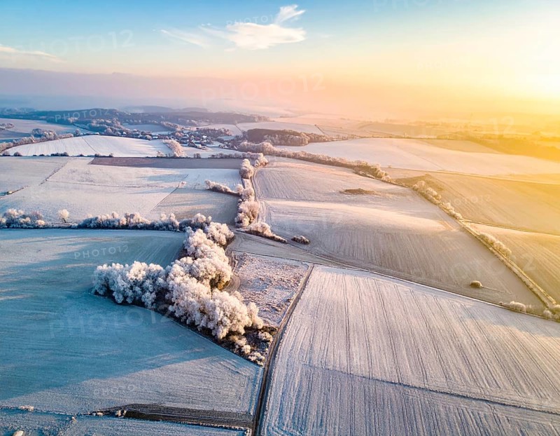 Bird Eye Perspective of Frost Covered Farmland. Seasonal Agricultural Scenery, winter and autumn scene, blue sky with golden light at sunrise, AI generated