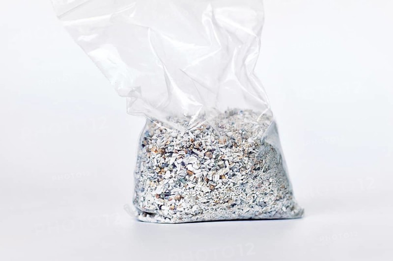 Plastic bag containing ash of a pet cat after cremation on white background