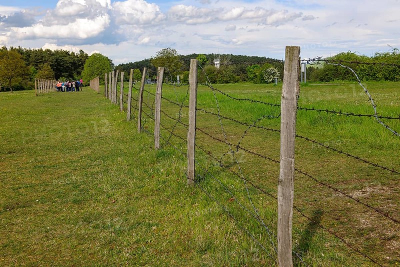 Partially reconstructed first border fence on the inner German border former zone border between West Germany Federal Republic and GDR East Germany with barbed wire between death strips, group of visitors on the left in the background, open-air museum museum Point Alpha, Rasdorf, Hesse, Geisa, Thuringia, Germany
