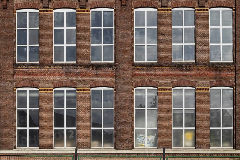 Symmetrical façade of an old brick building with large industrial windows, former Germania cotton mill, built in 1902 and a monument since 1995, Gronau-Epe, Münsterland, North Rhine-Westphalia, Germany