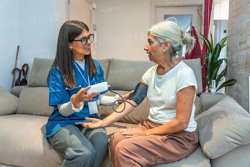 Healthcare professional checking blood pressure for an elderly woman in her home, providing essential medical support and demonstrating dedicated home care for senior well being