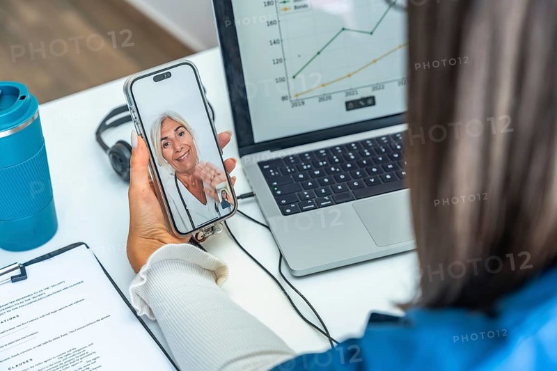Woman having an online telemedicine consultation with a senior female doctor on a mobile phone, using technology for remote healthcare and patient care from home