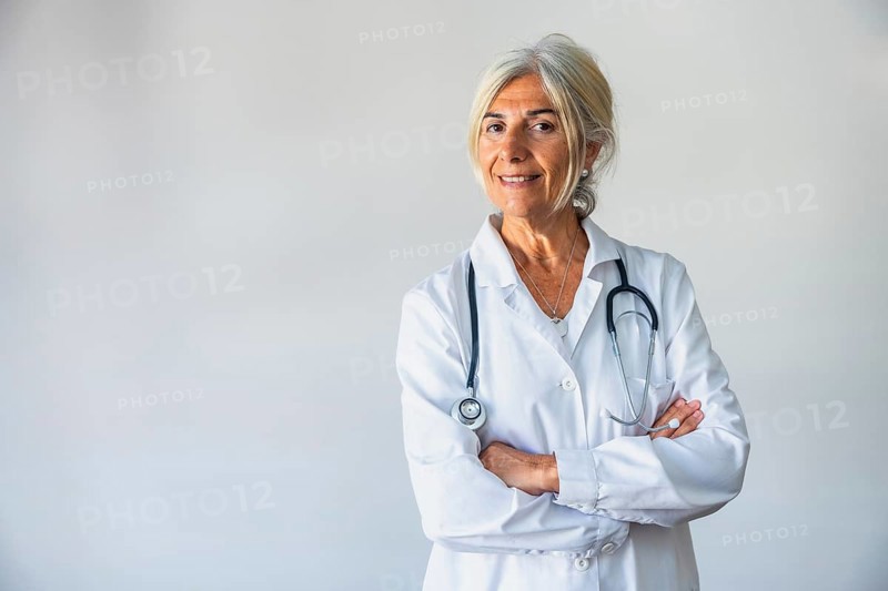 Senior woman doctor standing confidently with a stethoscope hanging around her neck, smiling at the viewer while her arms are crossed, conveying experience and trust in healthcare