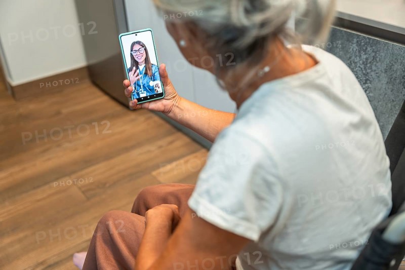 Senior woman using her mobile phone for a video consultation with a female doctor, accessing telemedicine from home for healthcare advice, support and remote medical care