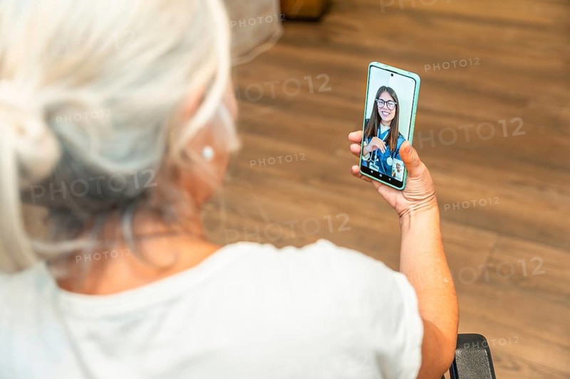 Senior woman is using a smartphone for a distant video consultation with a female doctor, experiencing modern healthcare and digital medicine services