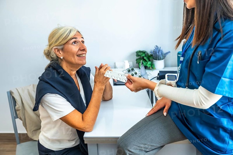 Medical professional giving a blister pack of pills to an elderly woman during a consultation, explaining treatment and promoting health awareness in a clinic setting