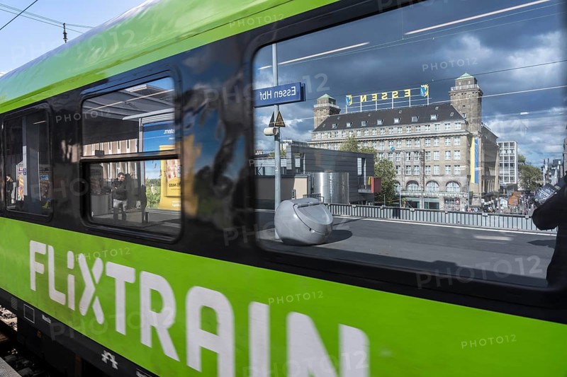 Flixtrain train on track 2 in Essen main station, reflection of the Handelshof building, city, platform in the window of the train, North Rhine-Westphalia, Germany