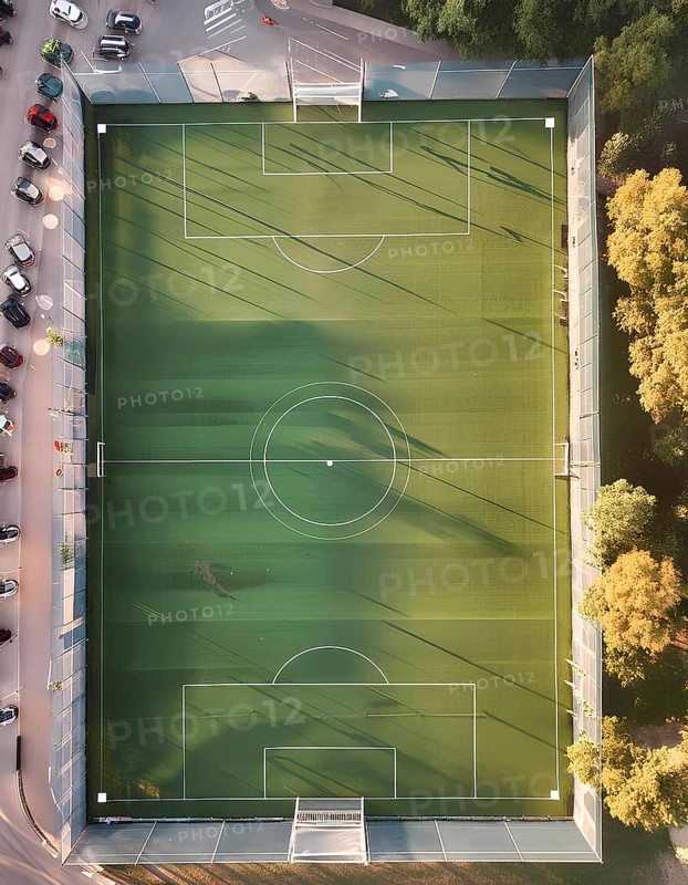 A soccer field with a green surface and white lines. The field is surrounded by a fence and trees, AI generated