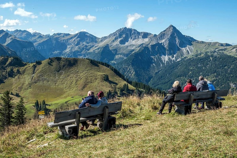 Hikers sit on bench at Neunerköpfle and look at the Allgäu Mountains, Tannheimer Valley, Tyrol, Austria