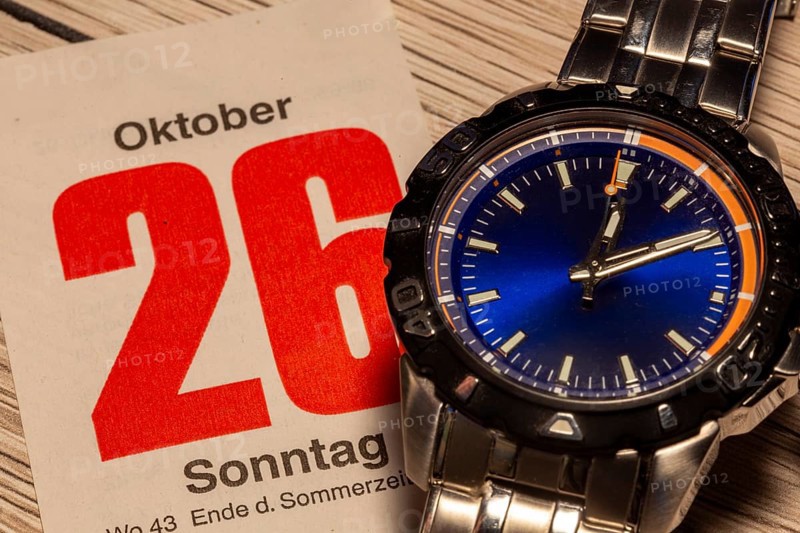 Wintertime 2025 time change: Close-up of a wristwatch and a sheet of a tear-off calendar showing the date October 26