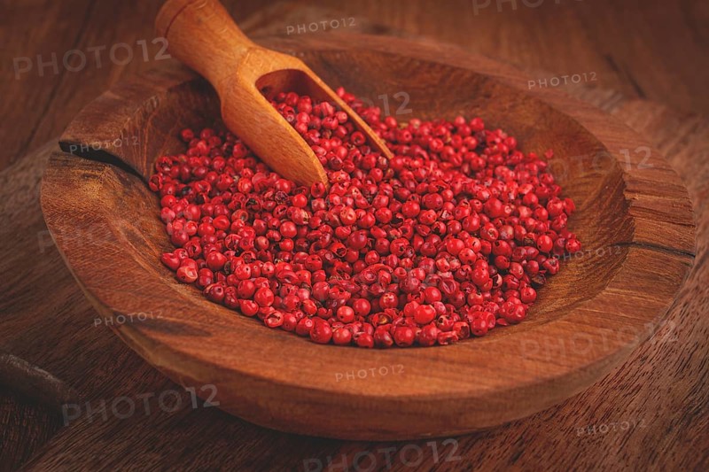 Bright red peppercorns, in a wooden bowl, with a small wooden tray