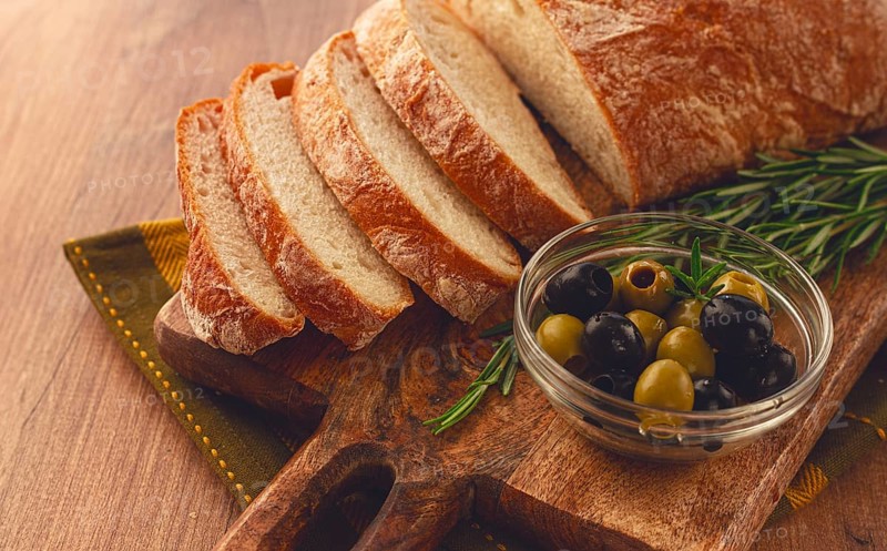 Sliced ciabatta, on a chopping board, with rosemary and olives, Italian bread, close-up, Italian cuisine, breakfast, no people