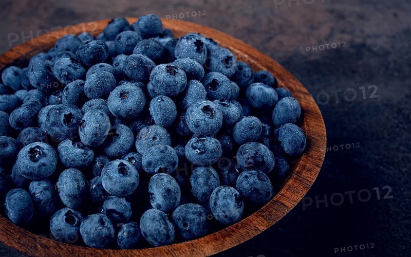 Fresh blueberries, in a wooden bowl, on the table, top view, close-up, no people