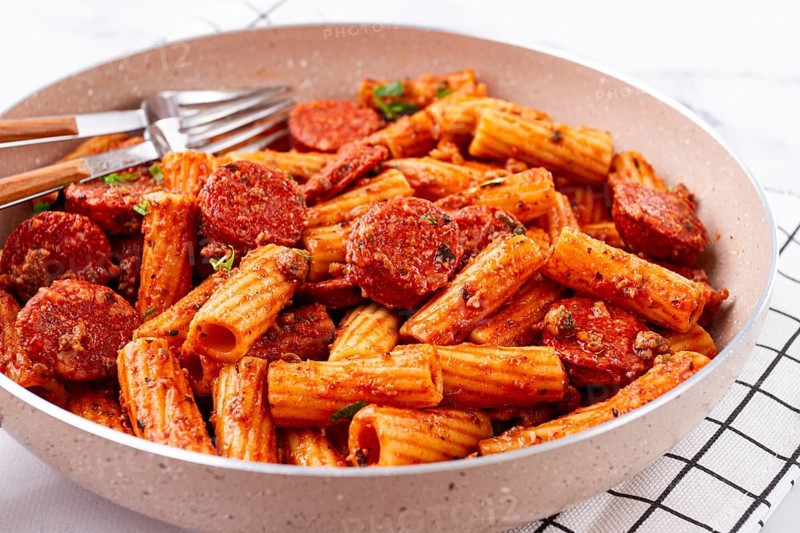 Rigatoni pasta with spicy sausage, and rich tomato sauce served, on a white plate, homemade