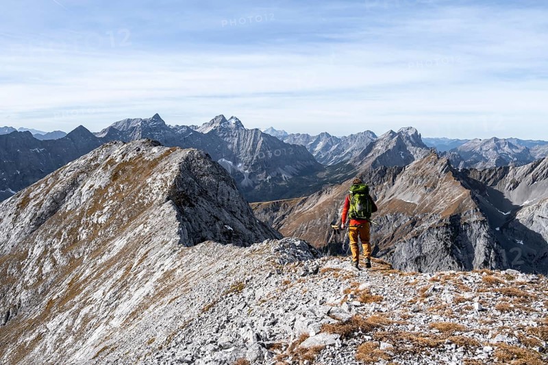 Hikers on the summit ridge of the Gamsjoch, behind rock faces of the Laliderer Spitze, eastern Karwendel, Tyrol, Austria