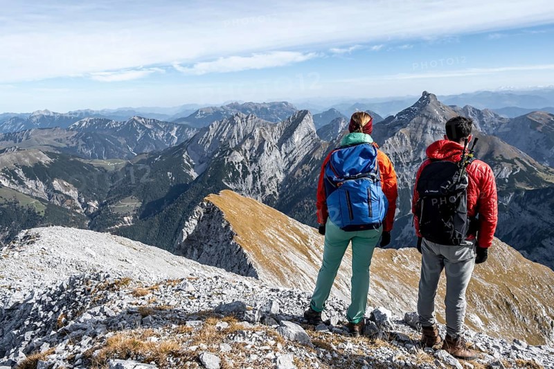 Two hikers on the summit of Gamsjoch look at the mountains, eastern Karwendel, Tyrol, Austria